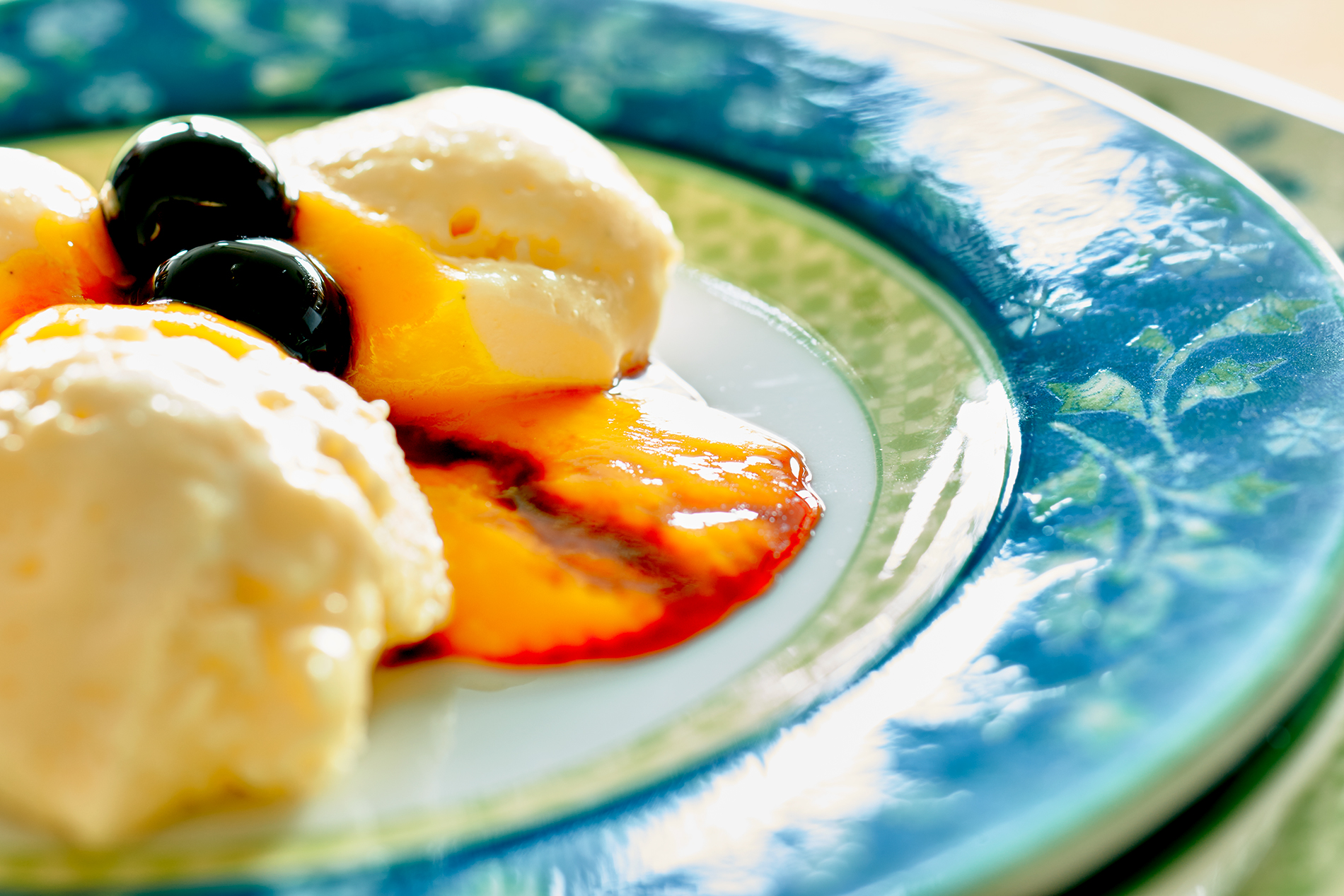 Bayrisch Creme mit Mango-Püree und Amarena-Kirschen auf einem blau-grünen Teller