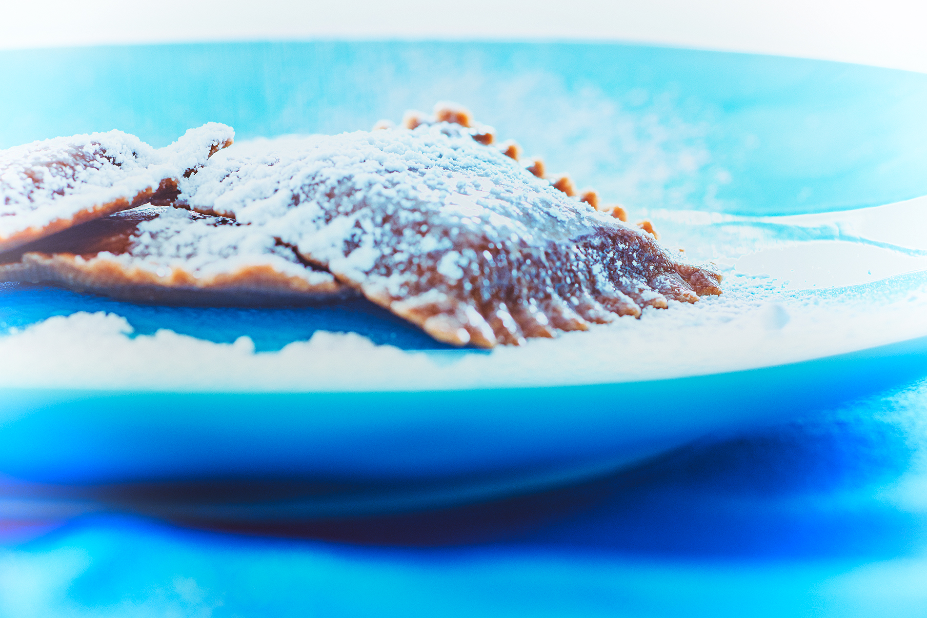 Schokoladen-Ravioli mit Puderzucker bestäubt auf einem blauen Teller