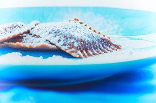 Schokoladen-Ravioli mit Puderzucker bestäubt auf einem blauen Teller